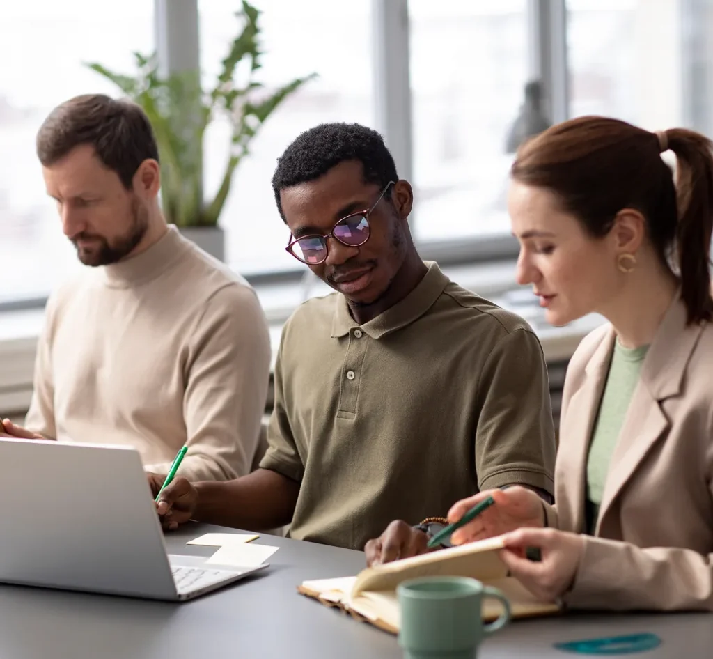 Drie collega’s zitten samen aan een bureau en bespreken de uitkomsten van het medewerkerstevredenheidsonderzoek.