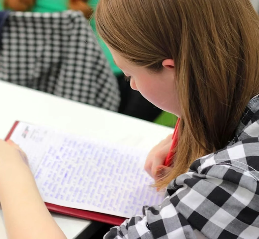 Vrouw schrijft met een rode pen aantekeningen in een schrift.